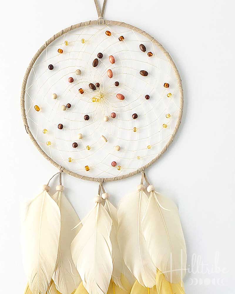 Dreamcatcher with white feathers and bead design on a white background
