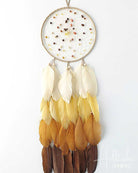 Dreamcatcher with yellow and brown feathers on a white background