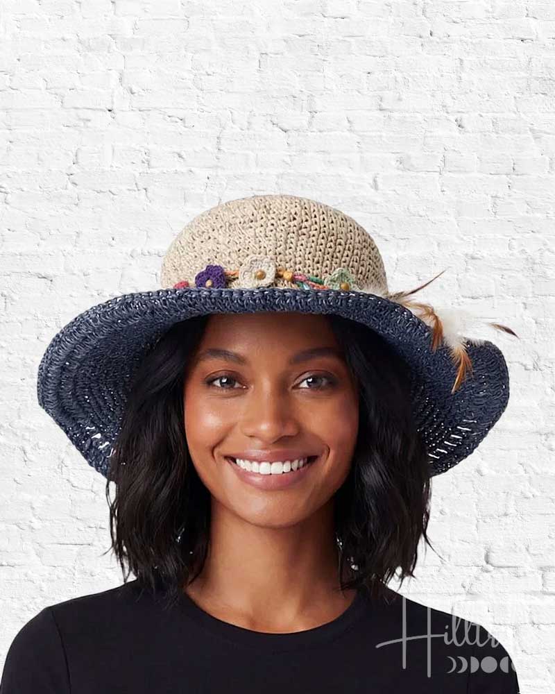 Woman wearing a blue and beige hat with feathers against a white brick wall