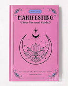 Pink book titled 'Manifesting Your Personal Guide' with a lotus flower and moon design on a white background.
