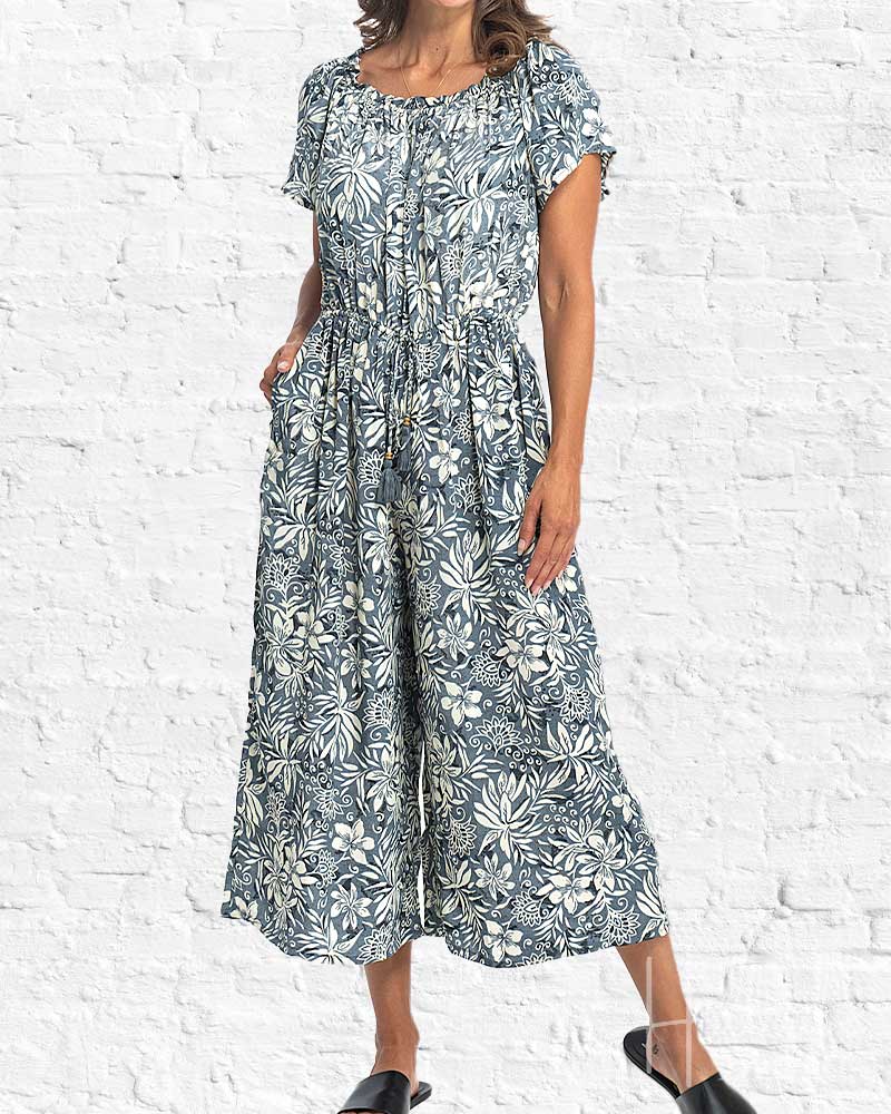 Woman wearing a floral dress against a white brick wall