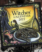 Llewellyn's Witches' Calendar 2027 cover featuring a witch sitting by a fire with a cat on a plate, illustrated in a vintage fantasy style with a black border and decorative symbols.