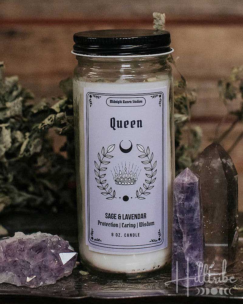 A jar candle labelled 'Queen' with sage and lavender scent, styled on a dark wooden surface with dried botanicals, crystals, and a wooden plank background.