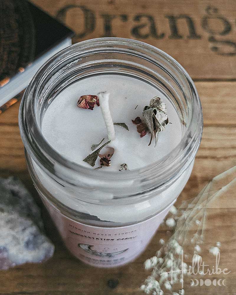 Candle in a glass jar with dried flowers on a wooden surface