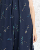 Navy blue dress with dragonfly pattern on a white brick wall background