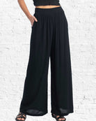 Black wide-leg pants worn by a person on a white brick wall background