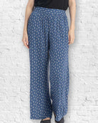 Person wearing blue patterned pants against a white brick wall.