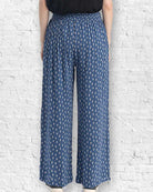 Person wearing blue patterned pants against a white brick wall.