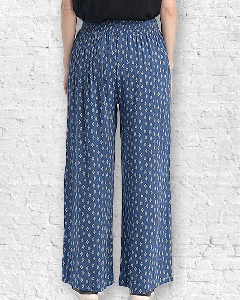 Person wearing blue patterned pants against a white brick wall.