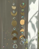 Decorative hanging with gold crescent moons and crystal beads against a light background