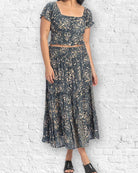 Woman wearing a dark floral dress against a white brick wall