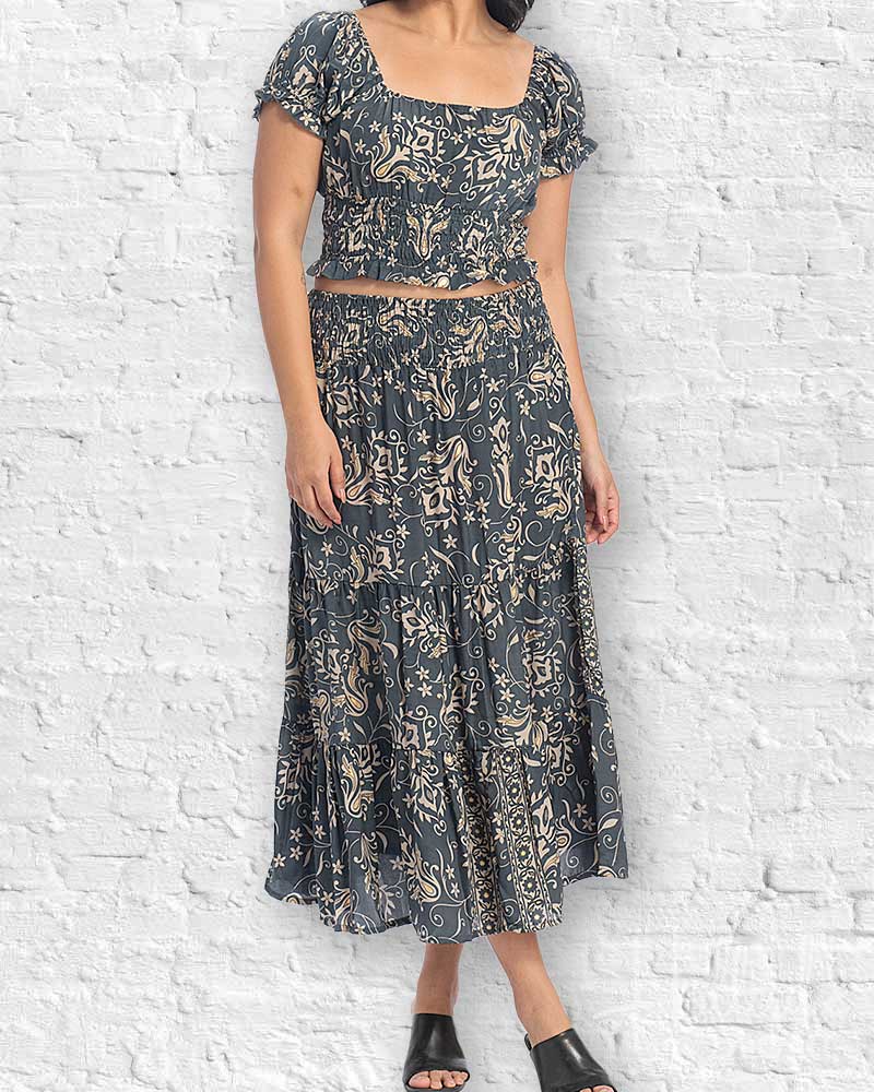 Woman wearing a dark floral dress against a white brick wall