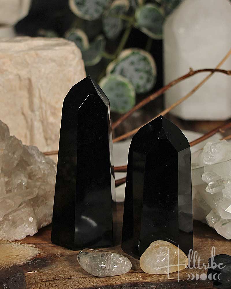 Two black crystal points on a wooden surface with decorative elements.