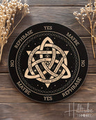 Decorative circular board with symbols and text on a wooden surface with dried flowers.