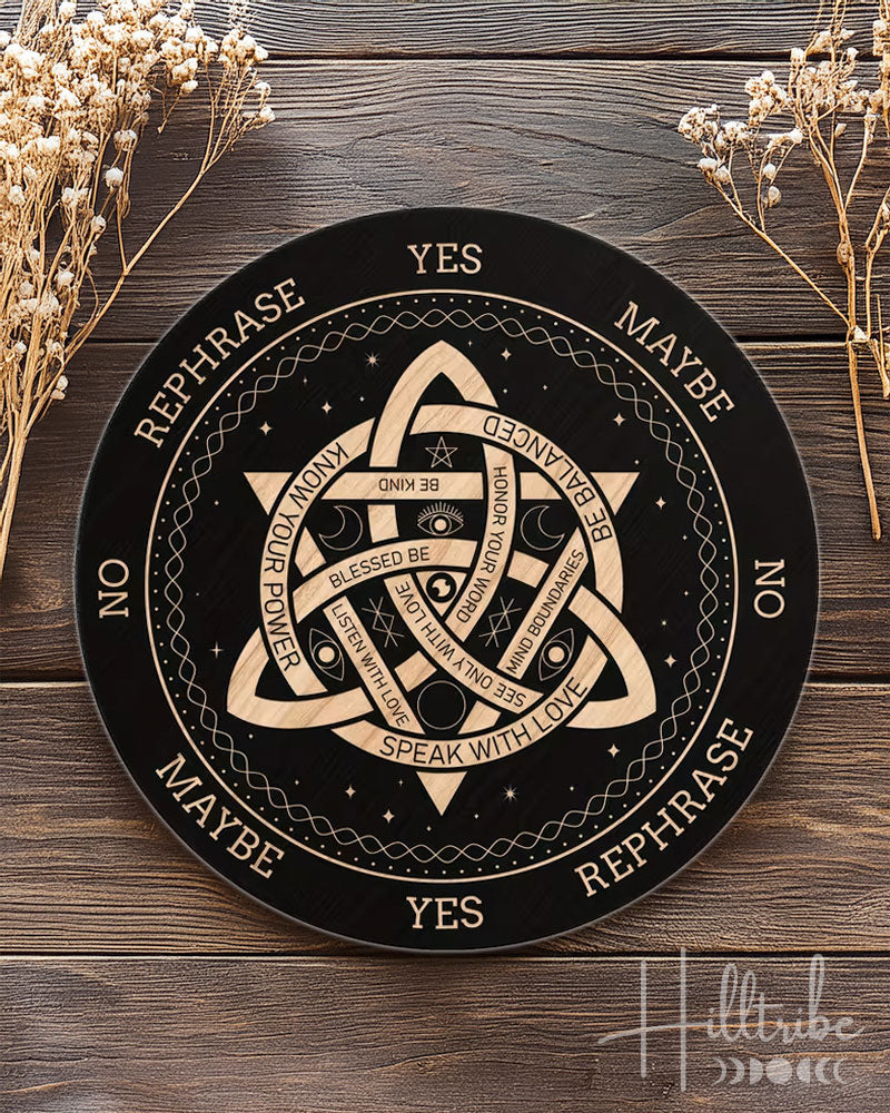 Decorative circular board with symbols and text on a wooden surface with dried flowers.