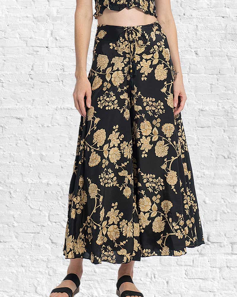 Black floral-patterned skirt worn by a person against a white brick wall.