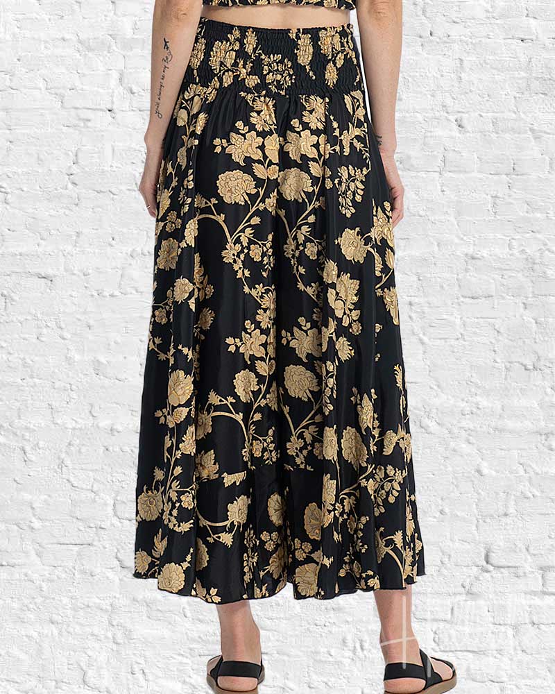 Black floral-patterned skirt worn by a person against a white brick wall.