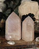 Two Pink Aura Quartz crystal towers on a wooden surface with blurred background