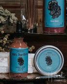 Collection of natural products, including candles, oils, and a crystal, on a wooden surface with a rustic background.