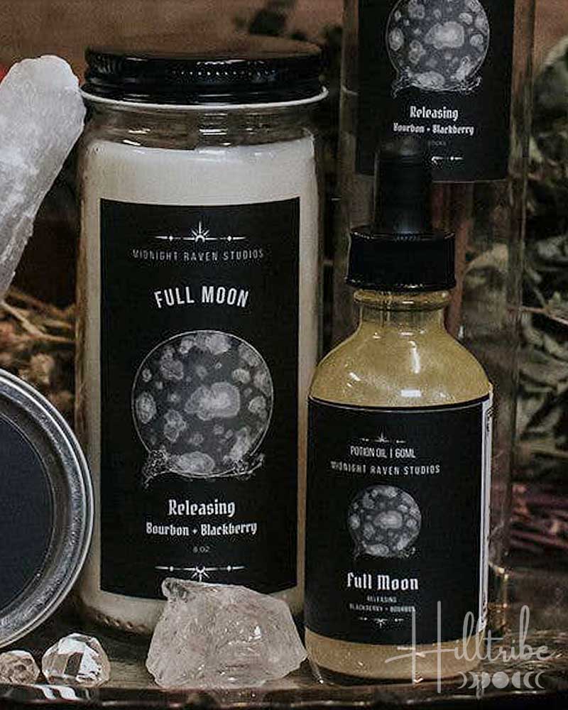 A curated product display of 'Still Water' brand wellness items, including a jar candle, a small bottle, a crystal ball, and a tumbler candle, arranged on a rustic wooden surface with dried botanicals and crystals.