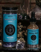 A styled product display of three natural wellness items from the brand Wild Harvest: a tall glass incense holder with a teal label, a jar of lavender bath salts, and a small dropper bottle of herbal tincture, all arranged on a rustic wooden surface with dried botanicals and crystals.