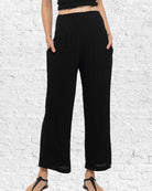 Person wearing black wide-leg pants against a white brick wall.