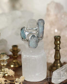 Silver ring with blue gemstones on a white crystal pedestal with a blurred background