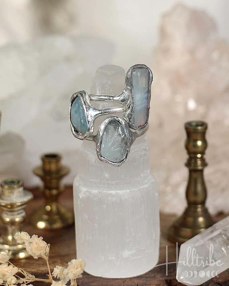 Silver ring with blue gemstones on a white crystal pedestal with a blurred background