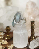 Crystal bottle with silver lid on a wooden surface with blurred background