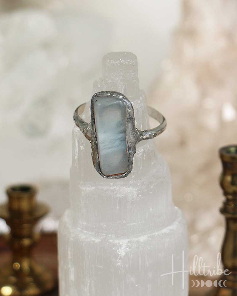 Silver ring with a blue stone on a crystal pedestal with a blurred background