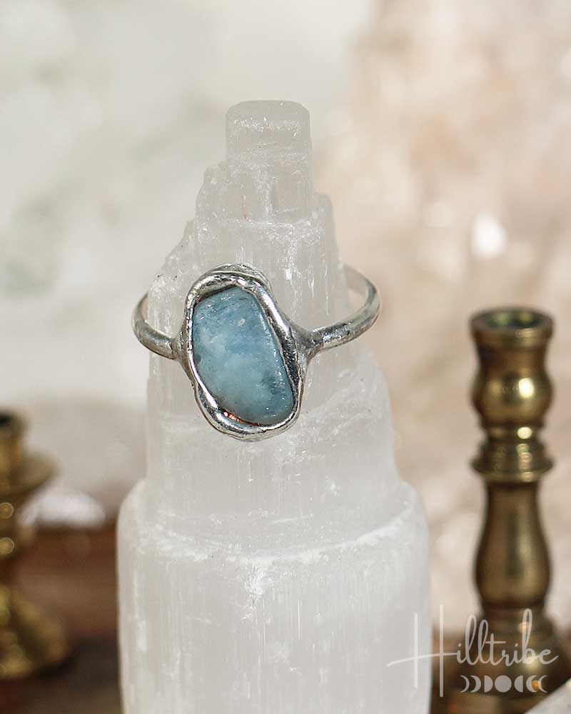 Silver ring with a blue stone on a white crystal, with 'Hilltribe' branding.