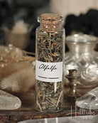 Glass bottle labeled 'Alfalfa' with cork lid on a wooden surface.