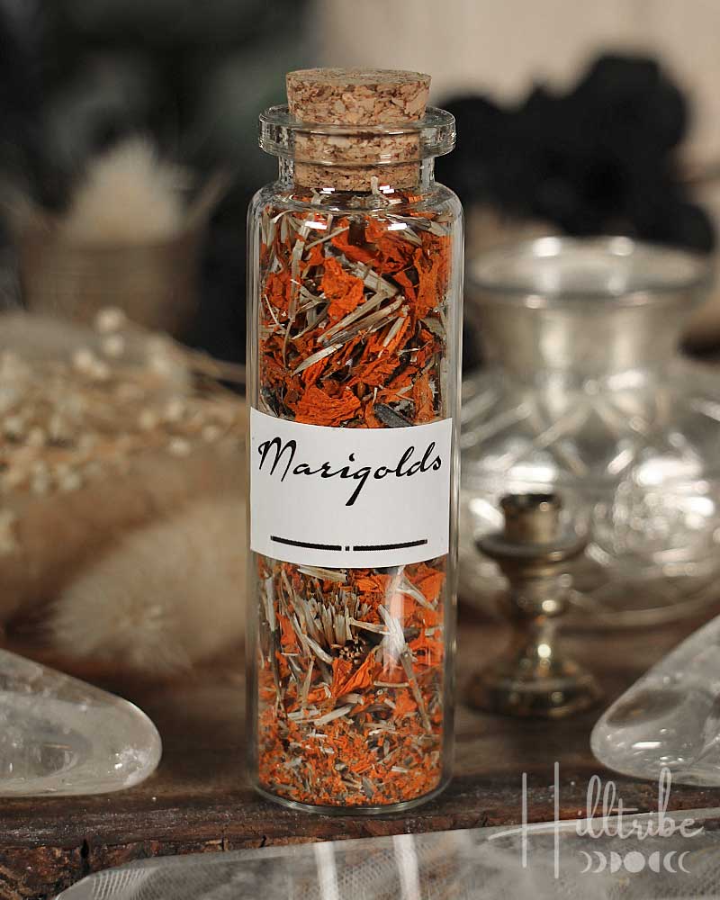 Glass bottle with cork lid filled with marigold flowers on a wooden surface.