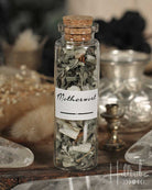 Glass bottle with cork lid containing dried herbs labeled 'Motherwort' on a wooden surface.
