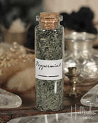 Bottle of peppermint leaves with a cork lid on a wooden surface.