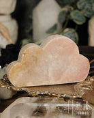 Rose Amethyst cloud-shaped stone on a gold stand with blurred background