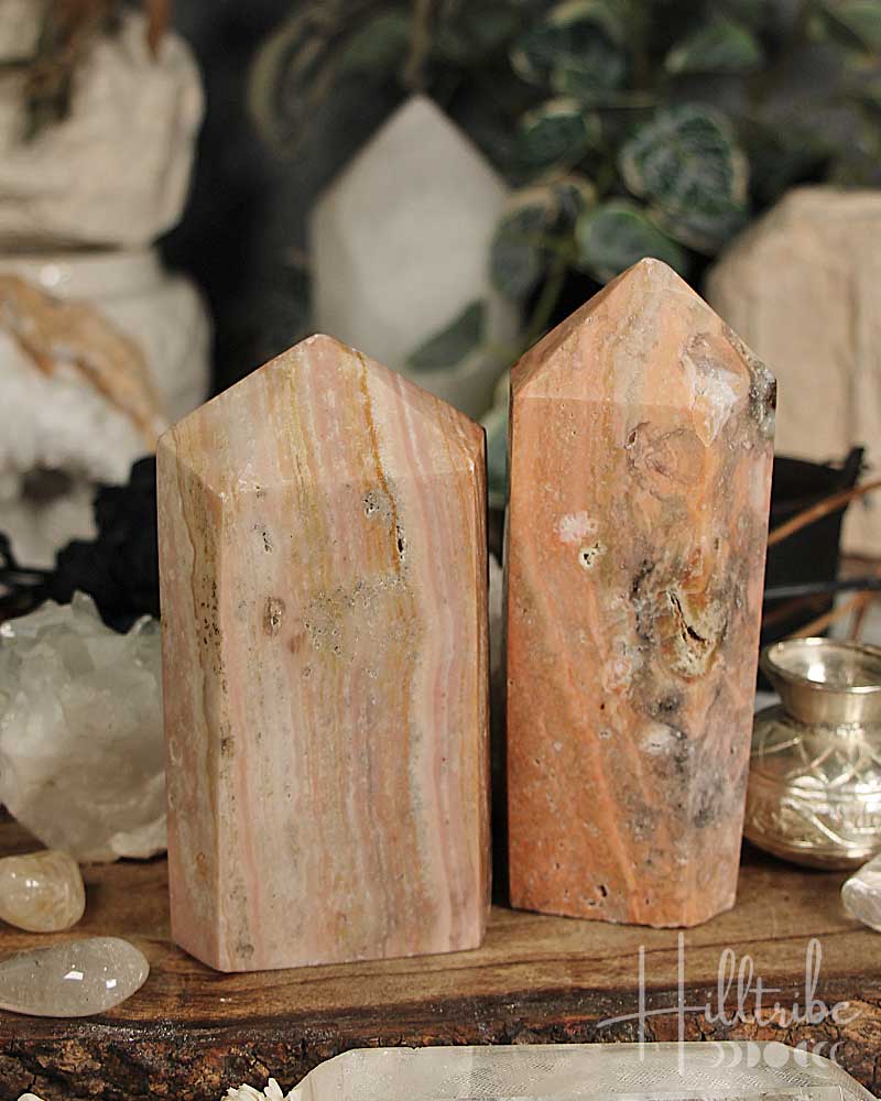 Two Rose Amethyst + Marble Jasper Tower on a wooden surface with a blurred background of decorative items.