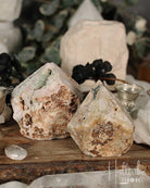 Two Rose Pink Amethyst Cut Base crystals on a wooden surface with blurred background