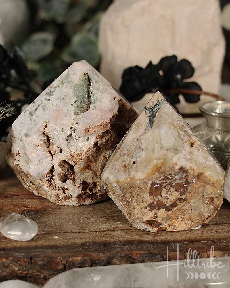 Two Rose Pink Amethyst Cut Base crystals on a wooden surface with blurred background