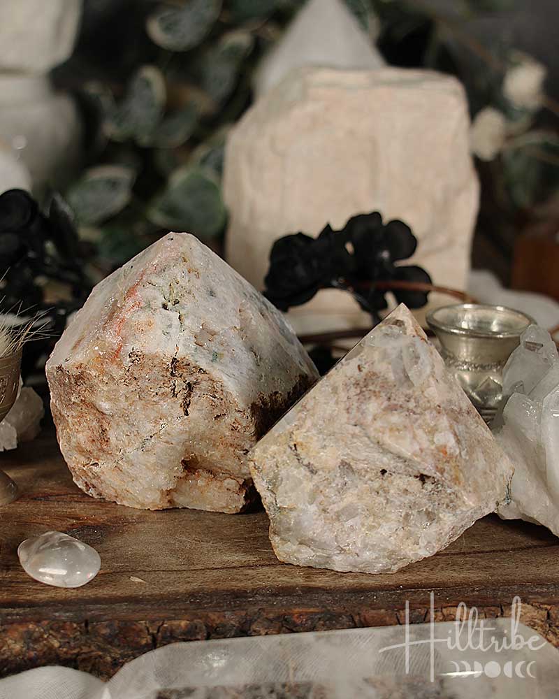 Two Rose Pink Amethyst Cut Base crystals on a wooden surface with blurred background