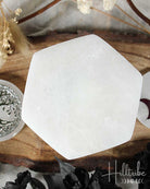 Hexagonal selenite crystal on a wooden surface with decorative elements