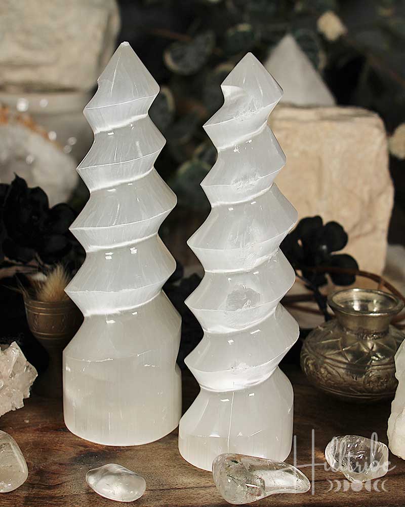 Two selenite crystal towers on a wooden surface with a blurred background