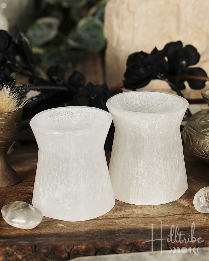 Two white selenite stone stands on a wooden surface with decorative elements.