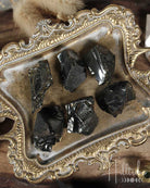 Natural Elite Noble Shungite rocks on a decorative tray with 'Hilltribe' branding.