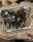 Natural Elite Noble Shungite rocks on a decorative tray with 'Hilltribe' branding.