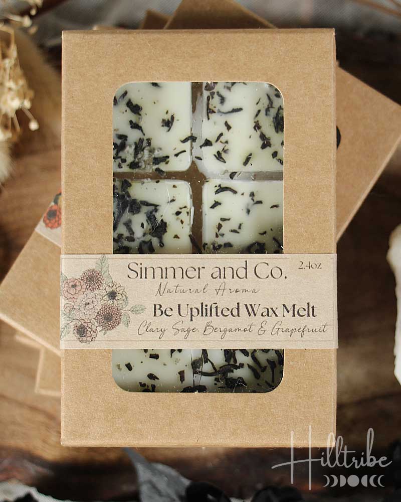 Box of 'Be Uplifted Wax Melt' by Simmer and Co. with visible ingredients on a brown background.