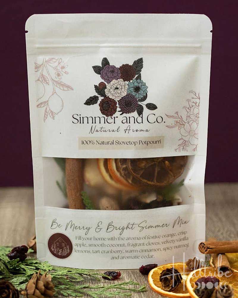 A stand-up pouch of Simmer and Co. Natural Aroma Poppyseed spice mix, labeled 'Be Merry & Bright Simmer Mix'.
