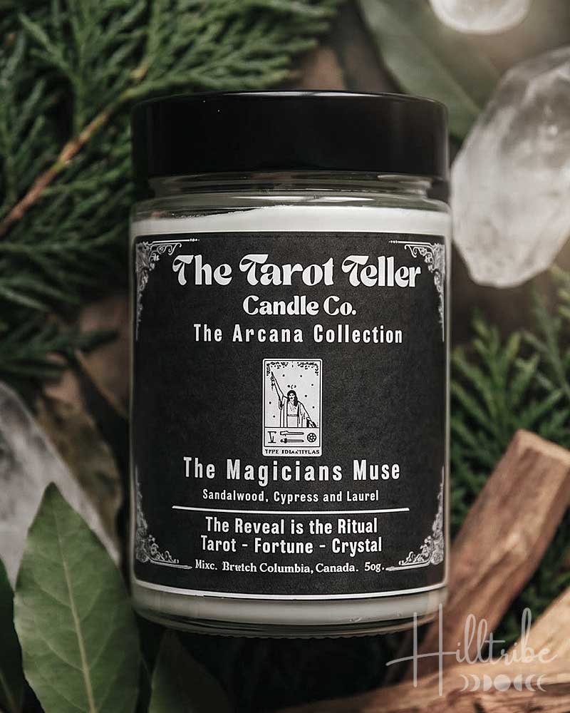 A jar candle labelled 'The Magicians Muse' by The Tarot Follower Candle Co. is centred among green leaves, cinnamon sticks, and clear crystals, with the text 'The Magician's Muse' at the top and 'A Ritual of Sandalwood, Cypress & Laurel' at the bottom.