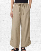Beige wide-leg pants worn by a person on a white brick wall background