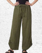 Person wearing olive green wide-leg pants against a white brick wall.